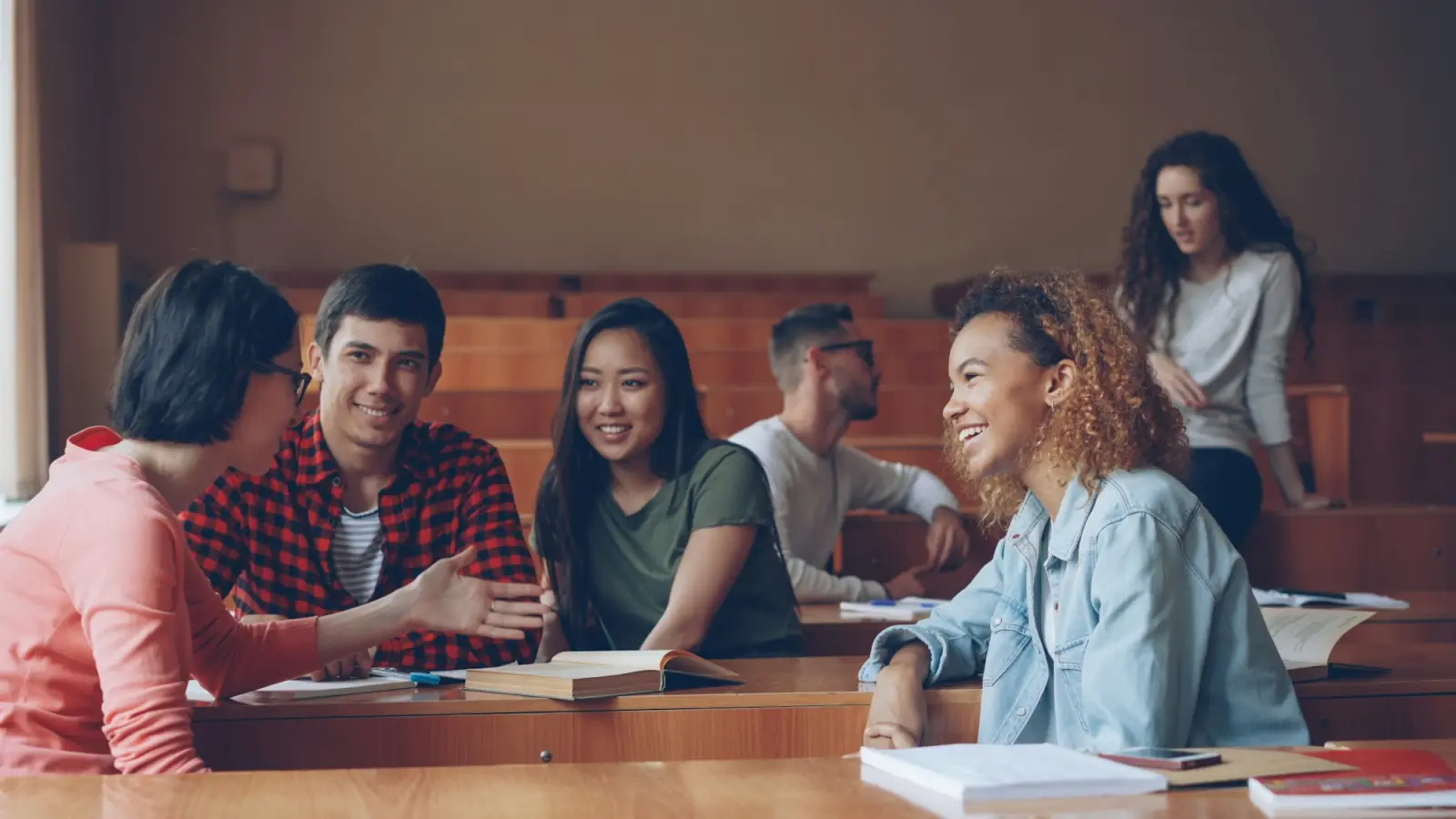Students laughing together during a class discussion in a tiered lecture hall