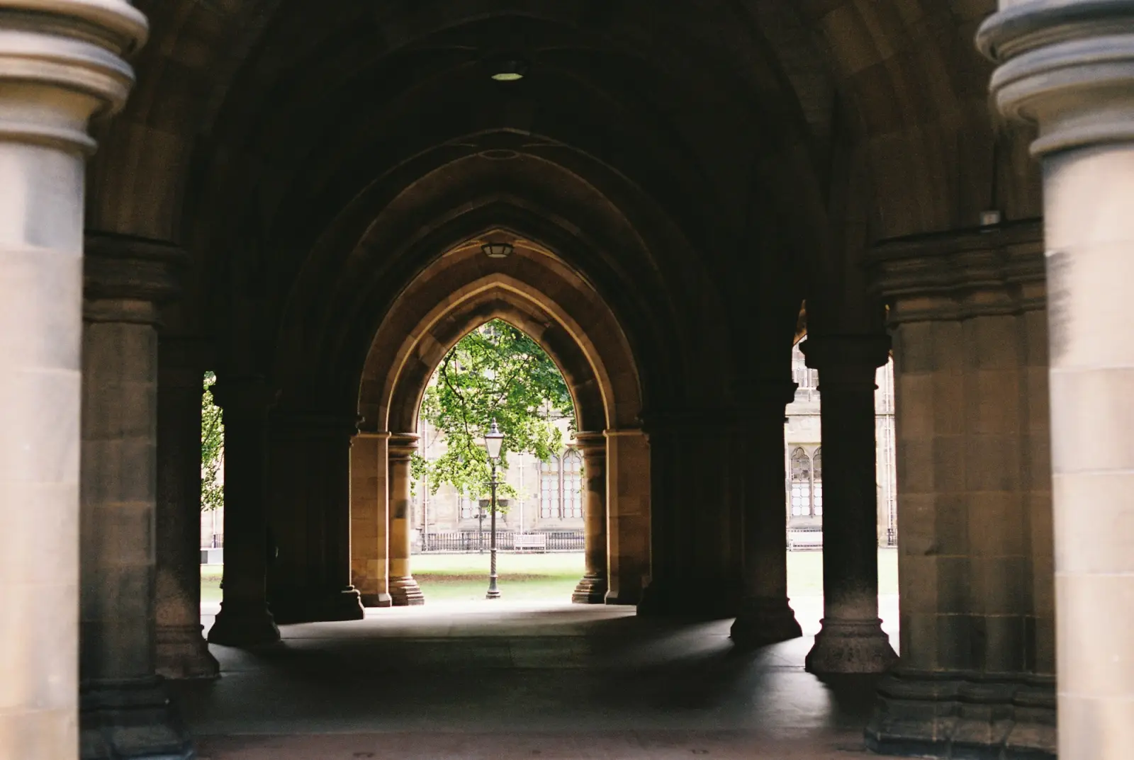 A stone arched walkway framing a green courtyard