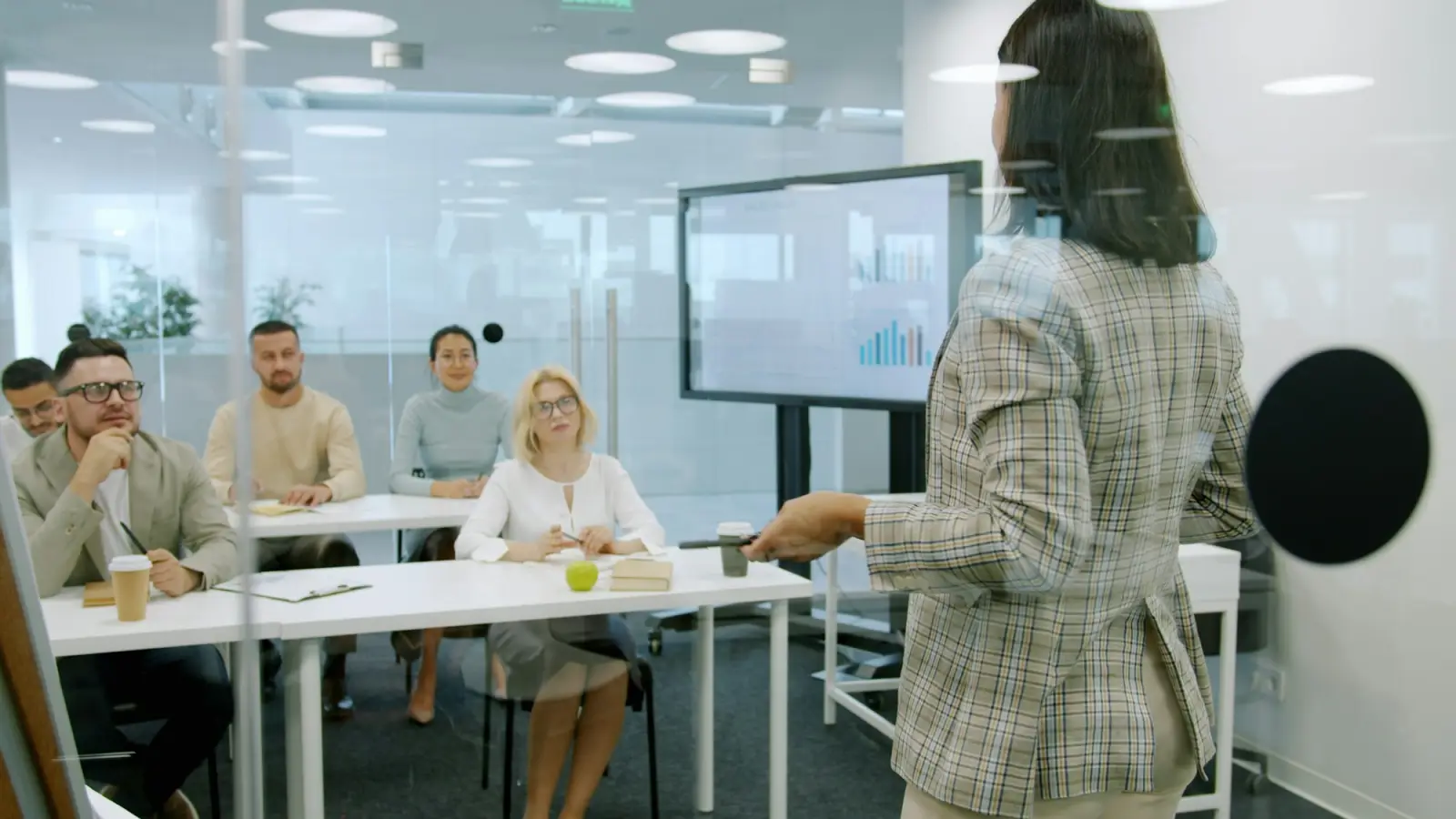 A woman presenting to an attentive group of professionals in a modern meeting room