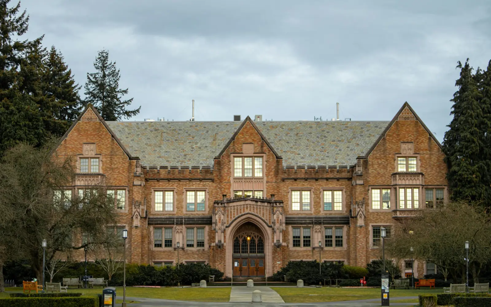 A brick collegiate building with a tower at dusk